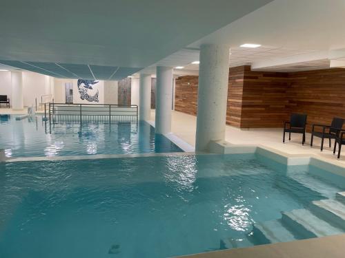 a large swimming pool with blue water in a building at Studio à Gourette avec piscine, 6 pers - Animaux admis - FR-1-860-44 in Gourette