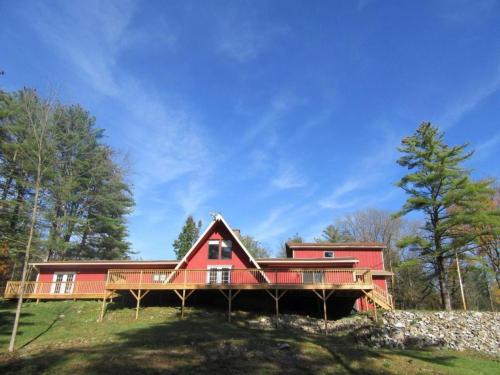 a large red house on a hill with trees at Charming Cabin Retreat in the Foothills of the Adirondacks in Fort Ann, New York in Fort Ann