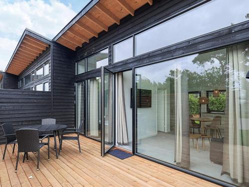 a house with glass doors and a table and chairs at 6 person holiday park home in Gilleleje in Gilleleje