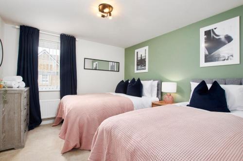 a bedroom with two beds with pink and white sheets at Central Coventry Stay, 3BR, Sleeps 9, Free Parking in Canley