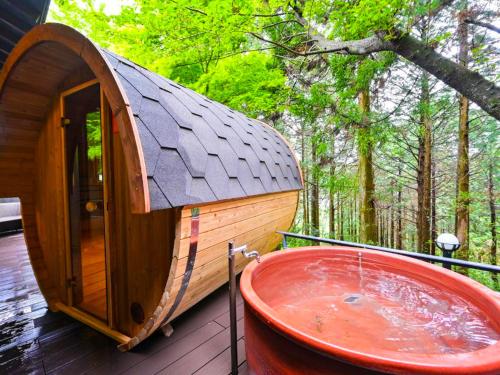 a small wooden cabin with a tub on a deck at Kaze no Tani no Iori in Gamagōri