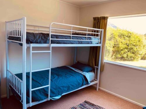 deux lits superposés dans une chambre avec fenêtre dans l'établissement Lake Hawea Family Holiday Home, à Lake Hawea