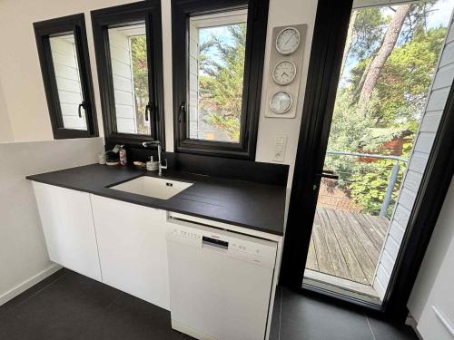 une cuisine avec un évier et deux fenêtres dans l'établissement Villa spacieuse pour 10 personnes avec WIFI dans le quartier de la Grière - FR-1-194-317, à La Tranche-sur-Mer