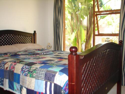 a bedroom with a bed with a quilt and a window at Shirleys Place in Brackenfell