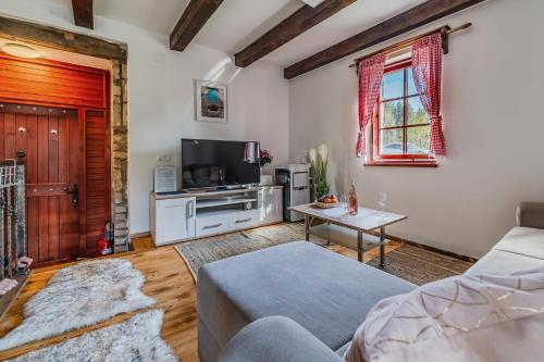 a living room with a couch and a tv at Nature Lodge With Sauna and Hot Tub - Happy Rentals in Tužno