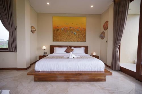 a bedroom with a bed and a painting on the wall at Gilded Palms Villa, Ubud Payangan, Bali in Payangan