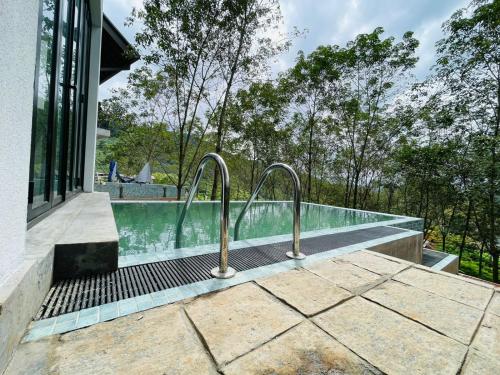 een zwembad met twee metalen rails naast een huis bij Leaf Olu Ella in Yatiyantota