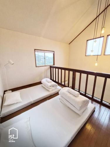 two beds in a room with two windows at Designer Island Villa with Panoramic Sea Views in Bizen