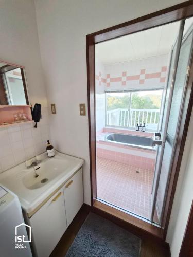 a bathroom with a sink and a tub with a window at Designer Island Villa with Panoramic Sea Views in Bizen
