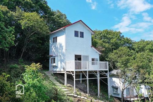 a white house on the side of a hill at Designer Island Villa with Panoramic Sea Views in Bizen