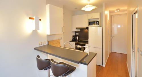 une cuisine avec des armoires blanches et un comptoir noir dans l'établissement Appart' Duguesclin, à Lyon