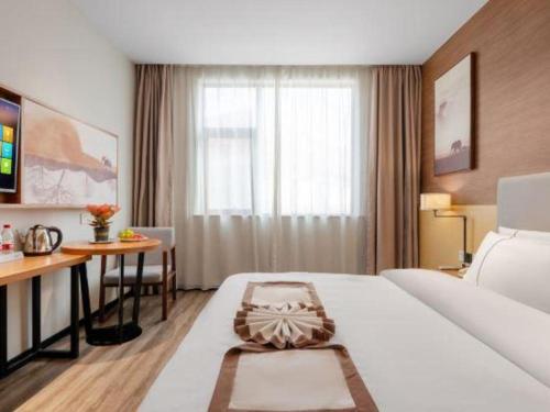 ein Hotelzimmer mit einem großen weißen Bett und einem Schreibtisch in der Unterkunft JTOUR Inn Yulin Railway Station Industrial Products Market in Yulin