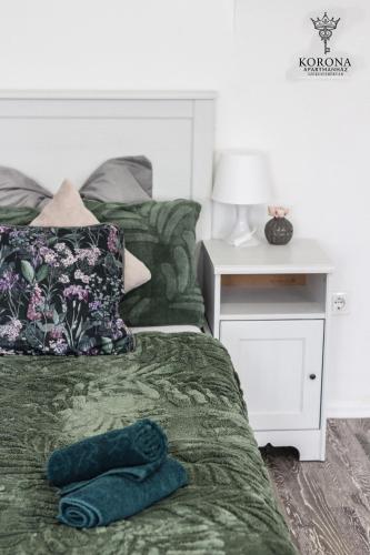 a bedroom with a bed with a green comforter and a night stand at Korona Apartman Székesfehérvár in Székesfehérvár