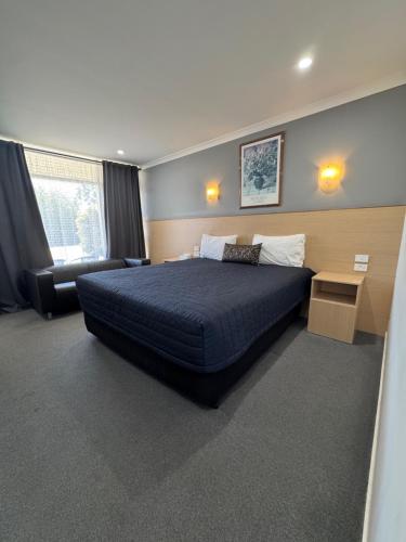 a bedroom with a large bed and a desk at The Sands Motel Adelaide in Adelaide