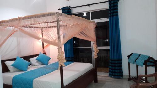 a bedroom with a canopy bed with blue pillows at New Rani Inn in Negombo