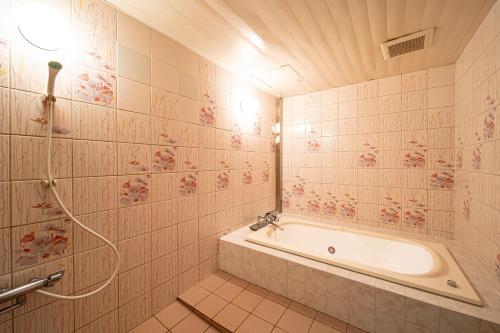 a tiled bathroom with a tub and a shower at ホテルミント羽島 in Hashima