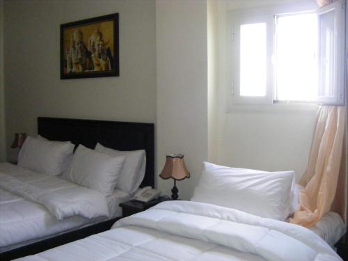 a bedroom with two beds and a window at Best View Pyramids Hotel in Cairo