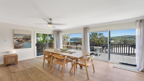 a dining room with a table and views of the ocean at Jean's Beach House Accom Holidays in Copacabana