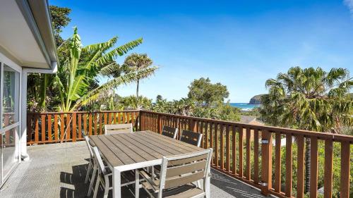 a wooden table and chairs on a balcony with the ocean at Jean's Beach House Accom Holidays in Copacabana