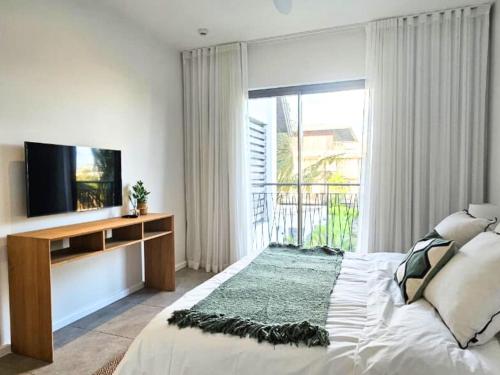 Ocean - Pool - BBQ - Resort - 3 Ensuite - Grand Baie في غراند بايَ: غرفة نوم بتلفزيون ونافذة كبيرة