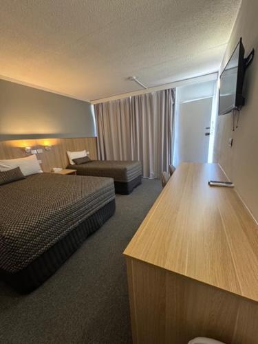 a hotel room with a bedroom with a bed and a couch at The Sands Motel Adelaide in Adelaide