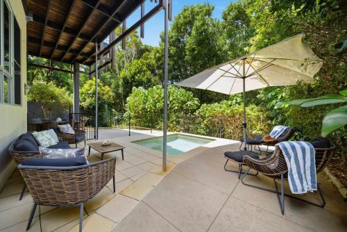 a patio with chairs and an umbrella and a pool at Family Beach House at Twin Waters Resort in Twin Waters