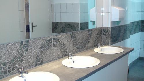 カトヴィツェにあるHostel Kamienna Centrumの青いタイルの共用バスルームに洗面台3つ