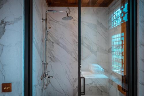a bathroom with a shower with white marble walls at Sanctum Peaks in Zhangjiajie
