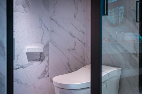 a bathroom with a toilet and a marble wall at Sanctum Peaks in Zhangjiajie
