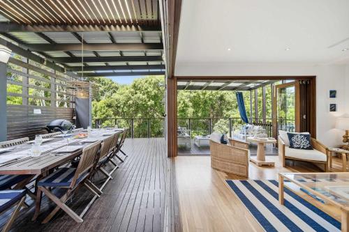 a dining room with a long table and a balcony at Family Beach House at Sebel Twin Waters Resort in Twin Waters
