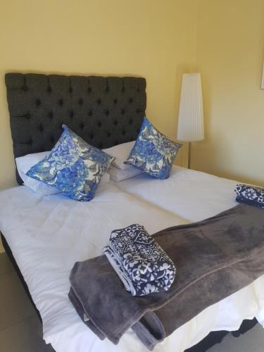 Una cama con almohadas azules y blancas. en 4Th On Boundary, en Gordonʼs Bay