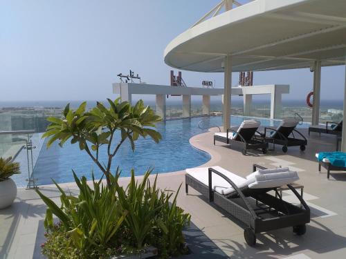 a beach with a pool, chairs and a boat at Grand Millennium Muscat in Muscat