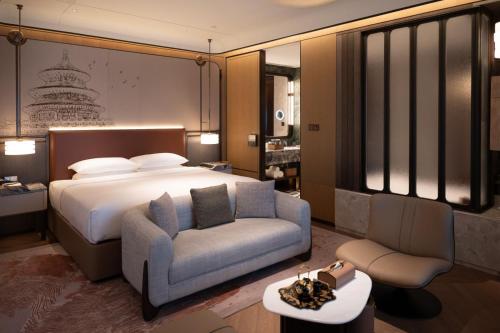 a bedroom with a bed and a couch and a chair at Jianguo Hotel HUANQIU in Beijing