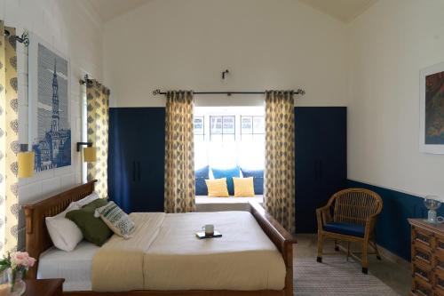 a bedroom with a bed and a chair and a window at Okka by Raho - A colonial style villa in Coorg in Siddapur