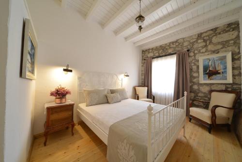 アラカティにあるKrem Hotelの白いベッドと石の壁が備わるベッドルーム1室