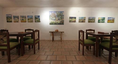 a room with tables and chairs and paintings on the wall at La Merced Del Alto in Cachí