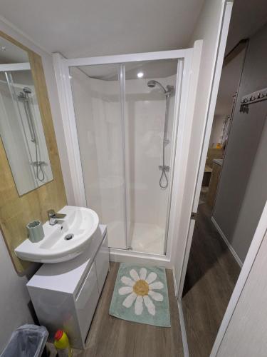 a white bathroom with a sink and a shower at Seascape Caravan in Kinmel Bay