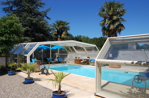 un poolhouse avec une serre et une piscine dans l'établissement Douce France 82, à Saint-Nicolas-de-la-Grave