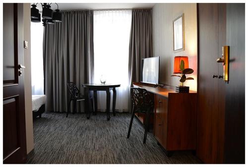 a hotel room with a desk and a window with a table at Apartamenty Róże i Zen in Toruń