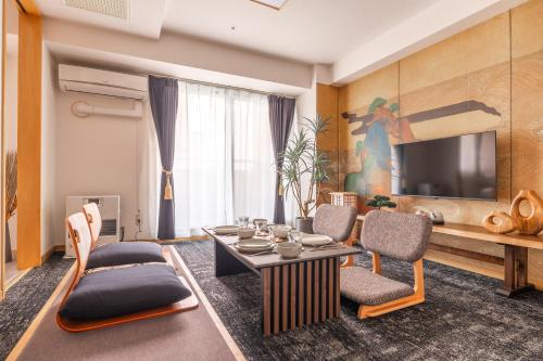 a living room with a table and chairs and a tv at Cozy Stay Sapporo Central Nakajima in Toyohira
