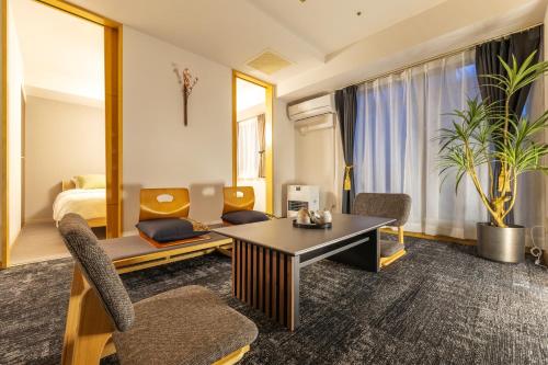 een hotelkamer met een bureau, stoelen en een bed bij Cozy Stay Sapporo Central Nakajima in Toyohira