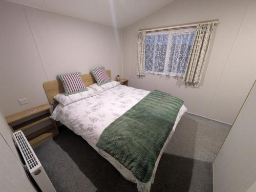 a bedroom with a bed with a green and white blanket at Seascape Caravan in Kinmel Bay