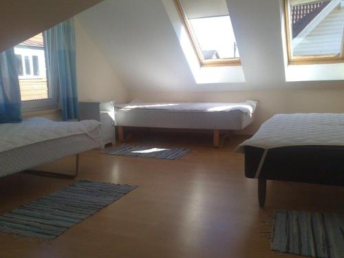 a attic room with two beds and two windows at Auli Beach Area Holiday Home in Pärnu
