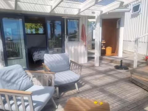 eine Terrasse mit einem Sofa und Stühlen auf einer Veranda in der Unterkunft Glamping with stunning sea view in Nelson