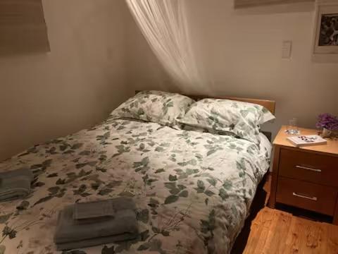 ein Schlafzimmer mit einem Bett und einem hölzernen Nachttisch in der Unterkunft Glamping with stunning sea view in Nelson