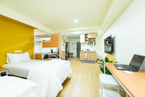a bedroom with two beds and a desk with a laptop at GL Sport Club Serviced Residence & Hotel in Bangkok