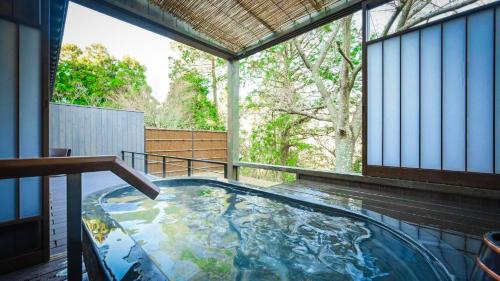 a hot tub in a house with a large window at Kaze no Tani no Iori in Gamagori