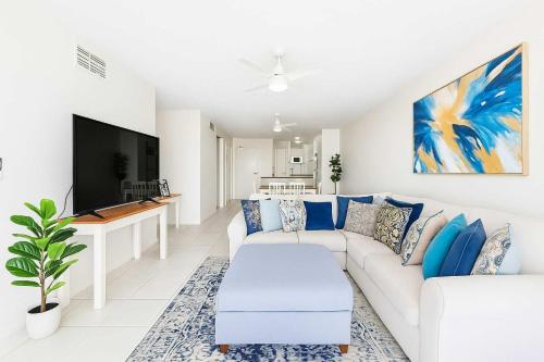 Una sala de estar con un sofá blanco y un televisor. en CBD Apartment with River Views Pool & Parking in Townsville, en Townsville