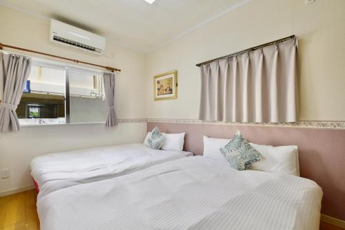 two twin beds in a room with a window at 海徒歩1分アメリカンビレッジまで7分周辺には飲食店多数の北谷エリアSunabeNest in Chatan