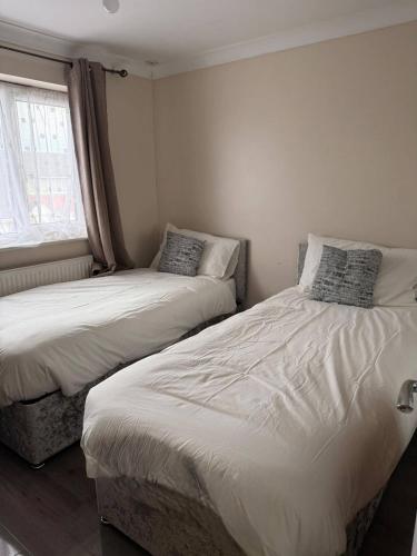 zwei Einzelbetten in einem Zimmer mit Fenster in der Unterkunft Peaceful Family Home in Tilbury with Garden Parking for 3 Cars in Low Street